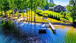 A lakeside property with a dock, a grassy area, and a house in the background. - Private Cove Lakefront Lake Anna Beach & Dock (Mineral)