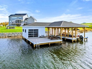 A houseboat with a covered deck, a garage, and a dock extending into a body of water. - Private Pointe Lakefront Lake Anna Beach, Dock (Mineral)