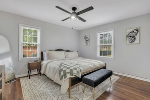 A bedroom with a bed, bedside tables, a ceiling fan, and large windows with blinds. - Statesboro Sunshine Retreat (Statesboro)