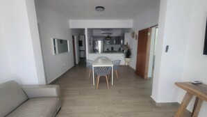 A modern apartment with a dining area, kitchenette, and a living room with a sofa and a small table. - Spacious 3BD Beach House 2 Blocks from Ocean Park (San Juan)