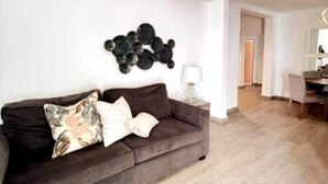 A living room with a dark brown sofa, a white lamp, and a wall-mounted decorative item.