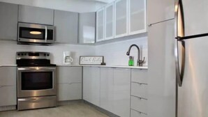 A modern kitchen with stainless steel appliances, white cabinetry, and a built-in microwave.
