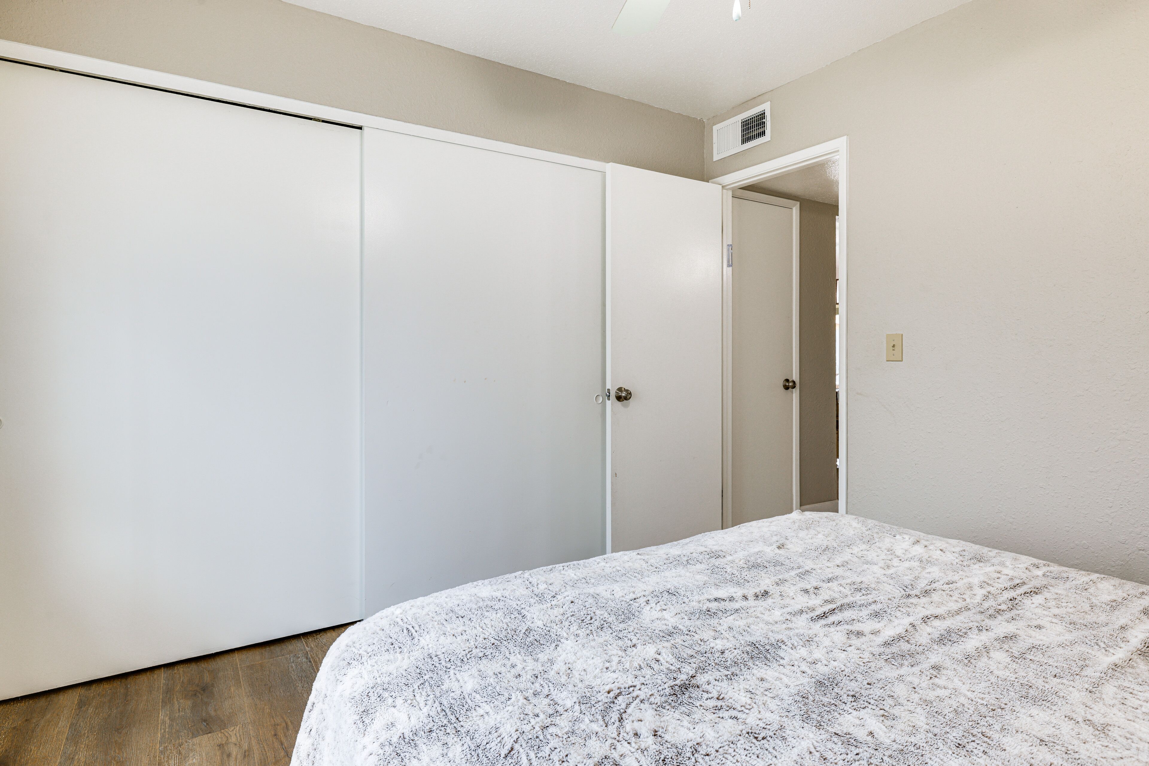 Un dormitorio con cama, armario y puerta que da a otra habitación.