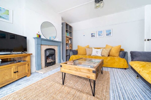 A living room with a television, a fireplace, a sofa, and a coffee table. - Spacious Home, Private Parking, Central Newquay (Newquay)