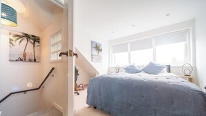 Quarto com cama, janela, escada e porta.