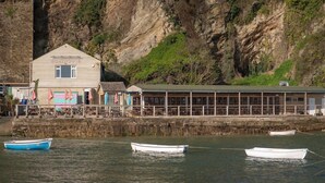 Um barco de abrigo com fachada de madeira e uma placa, ao lado de um edifício com telhado verde.