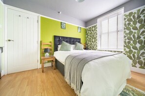 A bedroom with a bed, a nightstand, a wardrobe, and a window with blinds. - Spacious Home, Private Parking, Central Newquay (Newquay)