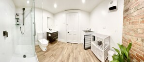 Ein modernes Badezimmer mit Duschkabine aus Glas, Toilette, Waschtisch mit Spiegel und Handtuchheizkörper.