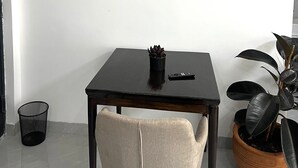 Habitación minimalista con una mesa negra, una sola silla y dos cuadros en la pared.
