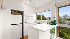 Una cocina moderna con armarios blancos, una isla integrada y vistas a la ciudad a través de amplias ventanas.