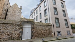 Un bâtiment en pierre avec une porte blanche et une rue pavée.