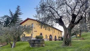 A yellow building with a stone wall, surrounded by trees and grass. - Casa Gioele A: A welcoming apartment situated in a quiet location, a few minutes from the town center, with Free WI-FI. (Umbertide)