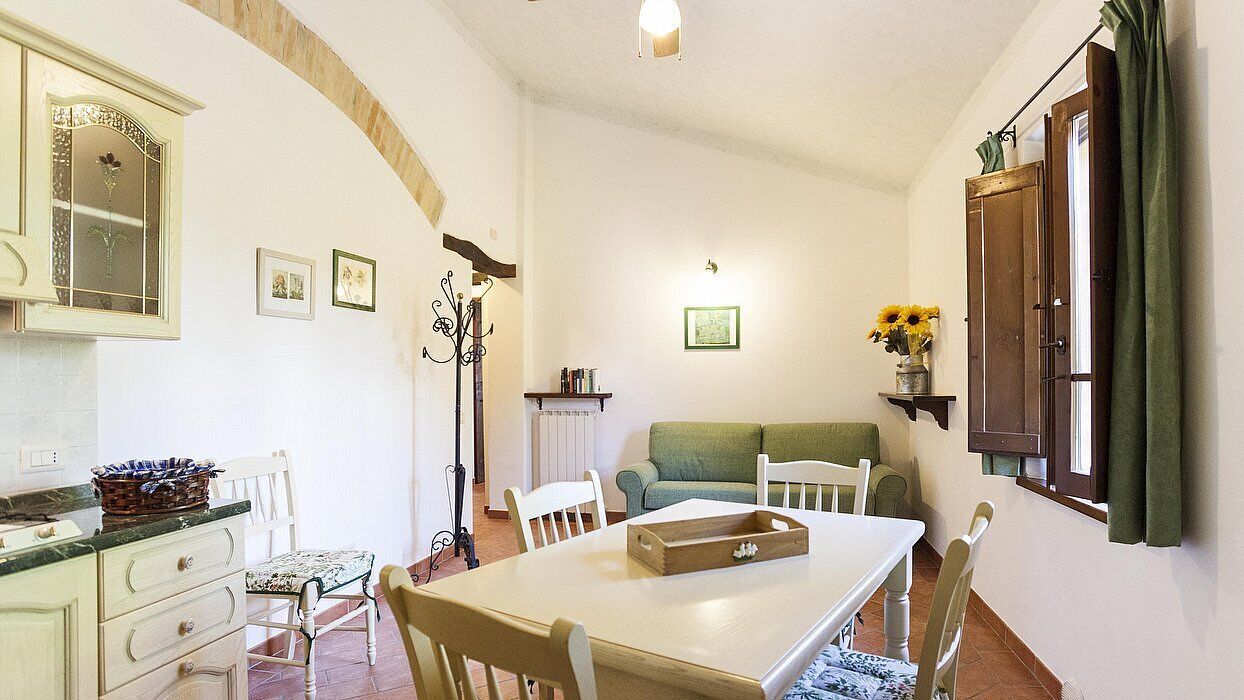 Un salon chaleureux avec une table à manger, des chaises, un canapé et une fenêtre avec des rideaux.