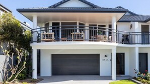 A two-story house with a balcony, a garage, and a small garden area. - Modern coastal charm in Kingscliff! (Tweed)