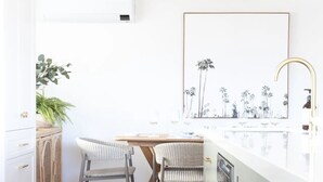 A modern kitchen with a white countertop, two wicker chairs, a wooden table, and a ceiling fan. - Modern coastal charm in Kingscliff! (Tweed)