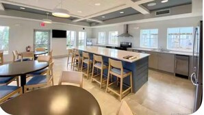 Una cocina moderna con una isla central, taburetes de bar y un comedor con mesas redondas.