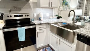 Una cocina moderna con electrodomésticos de acero inoxidable, armarios blancos y un corredor de suelo con motivos azules.