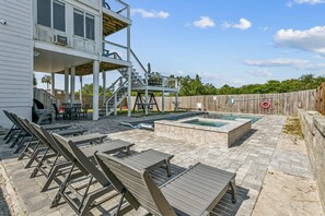 Ein Poolbereich mit Liegestühlen, einer Holzterrasse und einem zweistöckigen Gebäude mit Klimaanlage.