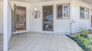 A covered patio with tiled flooring, a decorative tree mural, and a sliding glass door.