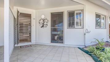 A covered patio with tiled flooring, a decorative tree mural, and a sliding glass door.