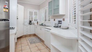 A modern kitchen with white cabinetry, a built-in microwave, and a stainless steel refrigerator.