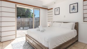A bedroom with a wooden bed, a large sliding glass door to a patio, and two framed artworks on the wall.
