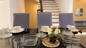 Een eettafel met stoelen, een vaas met bloemen en een trap op de achtergrond.