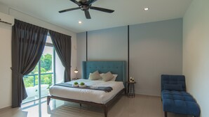 Een slaapkamer met een bed, een blauwe stoel, een plafondventilator en uitzicht op groen.