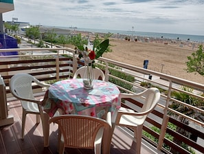 A balcony with a table, chairs, and a view of the beach. - Beachfront Modern Flat With sea View (San Michele al Tagliamento)