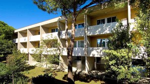 A multi-story building with balconies, surrounded by greenery. - Coastal Comfort Flat Just 400m From the Beach (San Michele al Tagliamento)