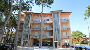 A multi-story building with balconies, a sign reading 'Al Toschetto,' and parked cars in front. - Modern one Bedroom Flat in Bibione - Beahost (San Michele al Tagliamento)