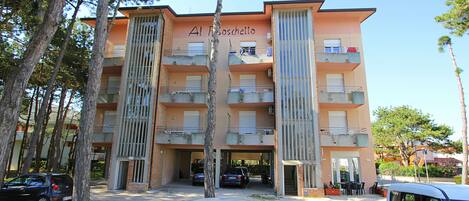 A multi-story building with balconies, a sign reading 'Al Toschetto,' and parked cars in front.