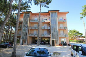 A multi-story building with balconies, a sign reading 'Al Toschettto,' and parked cars in front. - Modern one Bedroom Flat in Bibione - Beahost (San Michele al Tagliamento)