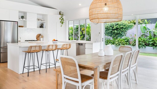 Une cuisine moderne dotée d’un îlot central, de tabourets de bar et d’une table à manger avec des chaises.