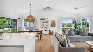 Un vaste espace de vie comprenant un grand canapé, une table à manger et un îlot de cuisine.