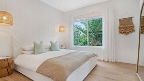 Une chambre avec un grand lit, une fenêtre avec des rideaux, une lampe de chevet et une décoration murale en tissu tissé.