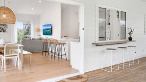 Une cuisine moderne avec des meubles blancs, une grande fenêtre et un coin bar équipé de tabourets.