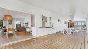 Un intérieur spacieux avec un plancher en bois, des murs blancs et un coin cuisine équipé de tabourets et d’un bar.