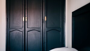 Een kamer met een grote donkerhouten garderobe, een bed met wit beddengoed en een witte wand.