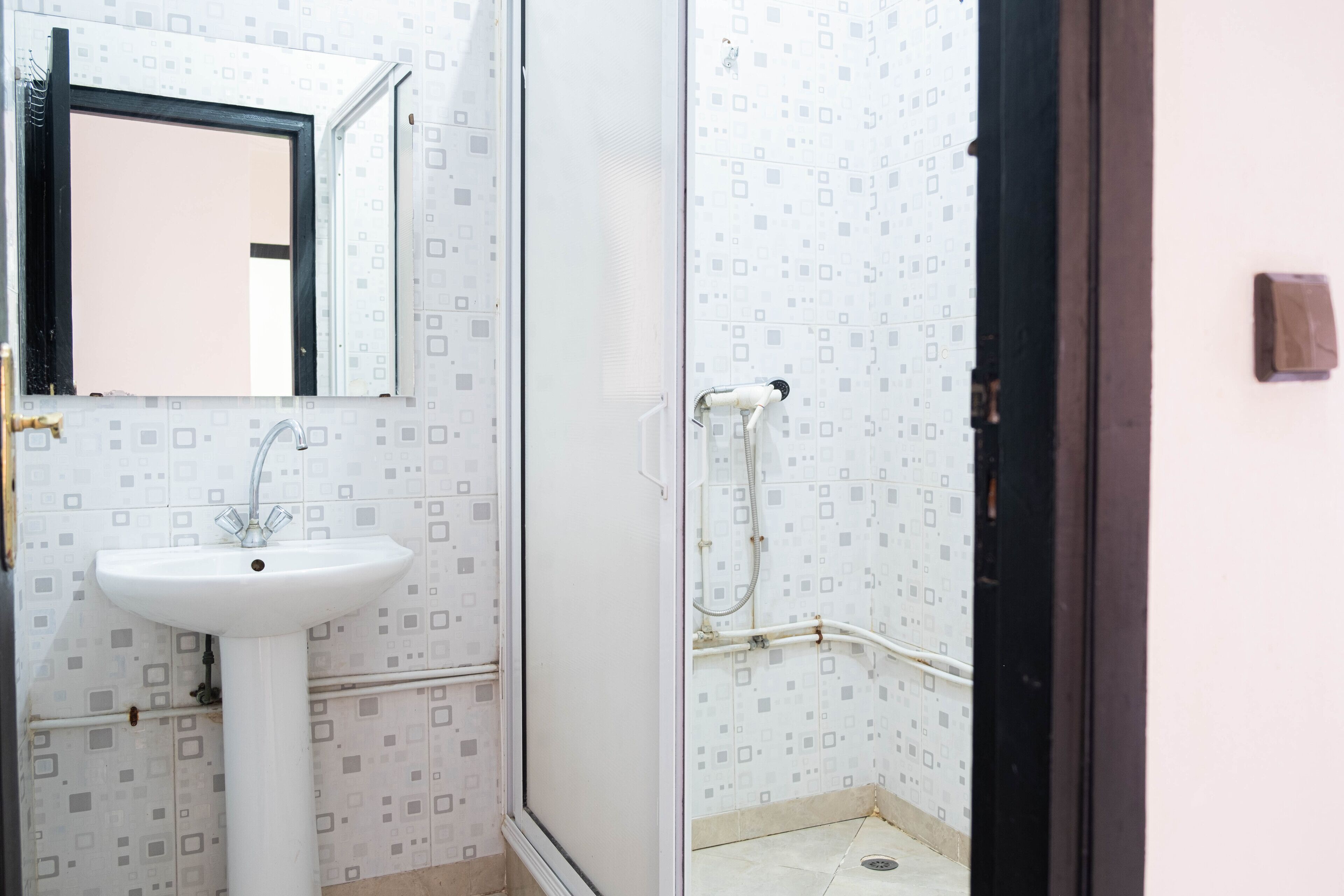 A bathroom with a sink, mirror, and shower.