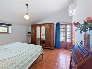 Un dormitorio con cama, armario, ventana y una planta en maceta.