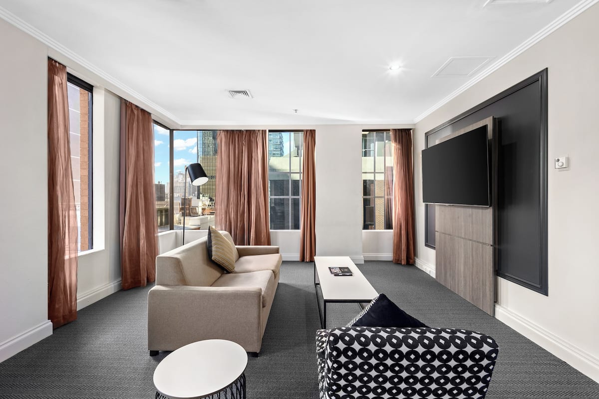 Ein modernes Hotelzimmer mit einer Couch, einem Sessel und einem Flachbildfernseher.