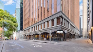 Un edificio moderno con entrada en esquina, ventanas grandes y un letrero que indica un restaurante o cafetería.
