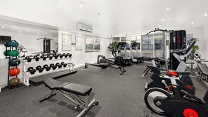 Un gimnasio moderno con diverso equipo de ejercicios, como mancuernas, banco y máquinas de cardio.