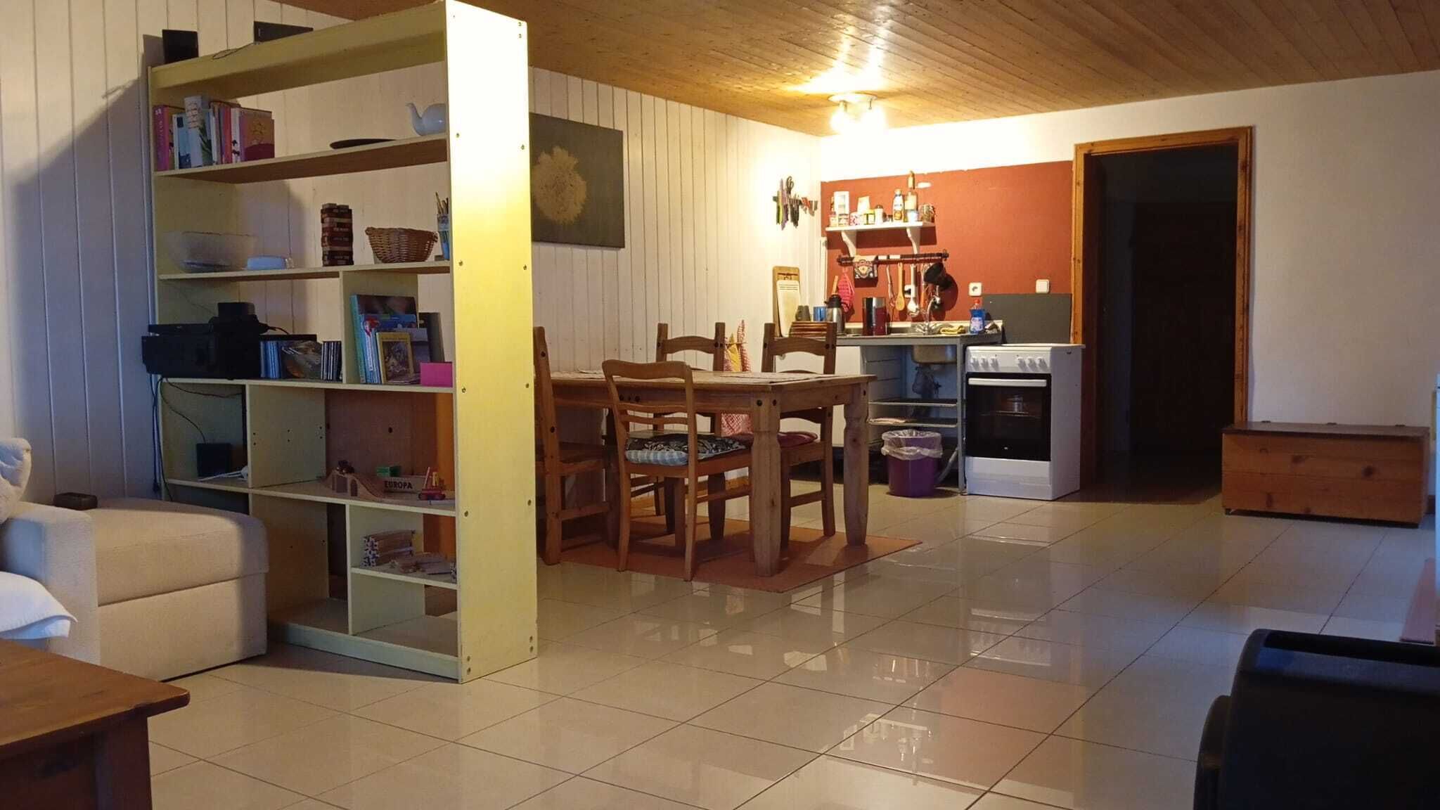 Un salon chaleureux comprenant un coin repas, une bibliothèque, une cuisine avec cuisinière et un plafond en bois.