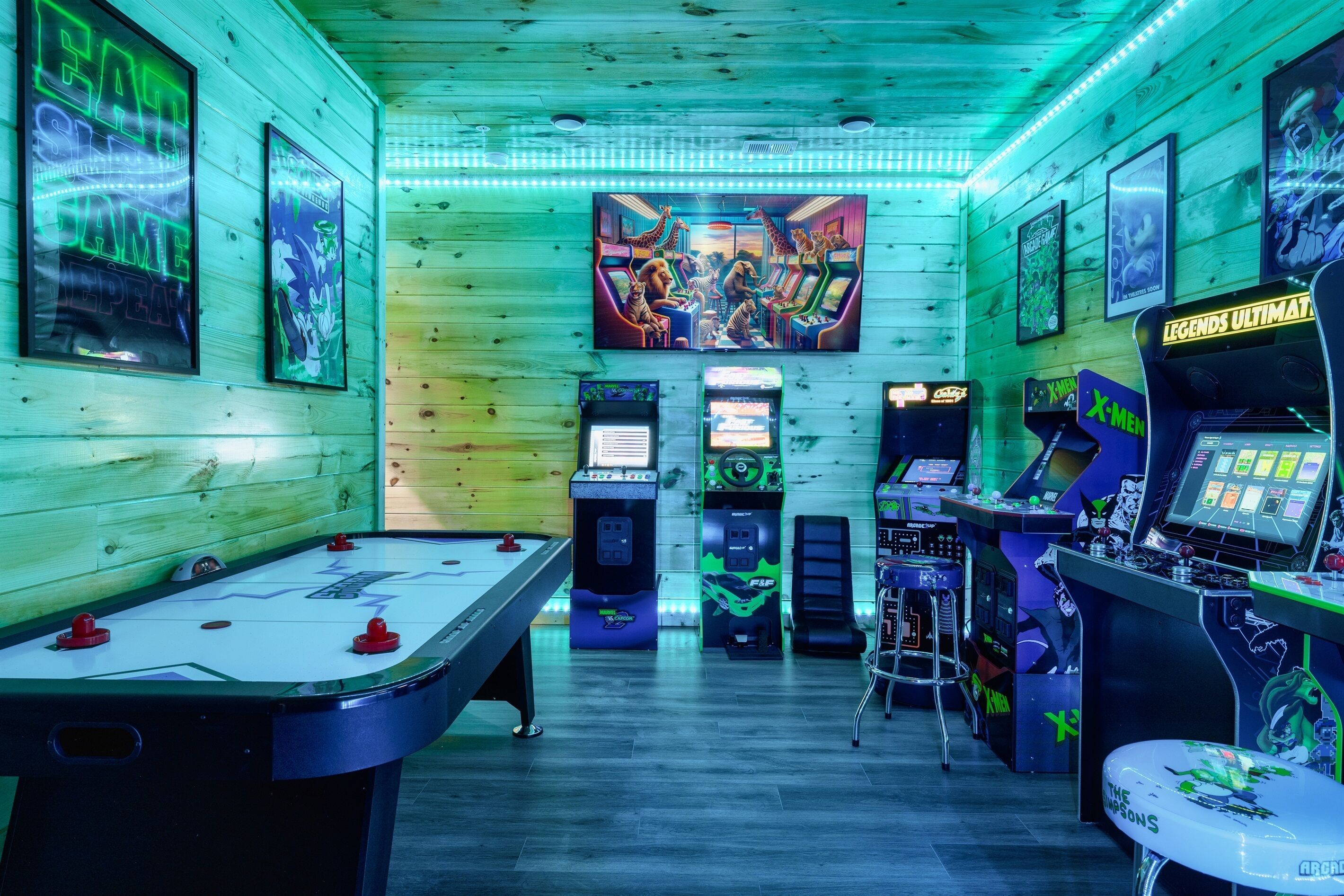 A room with a foosball table, arcade machines, and a large mural on the wall.