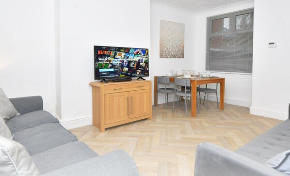 Relax in this stylish living room with a flat-screen TV, comfortable sofa, and dining area.