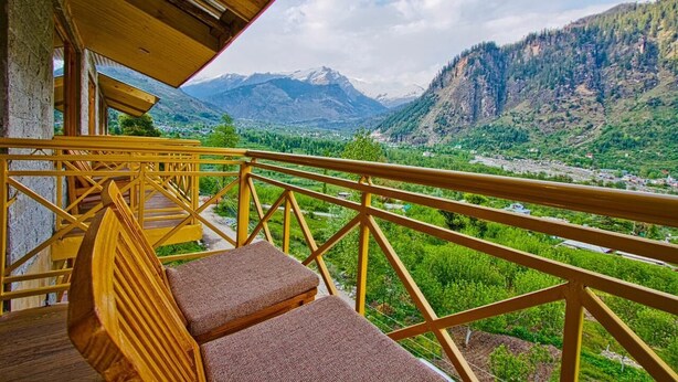 Un balcón de madera con vistas a un valle y montañas.