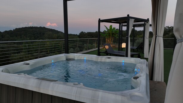 A hot tub on a deck with a pergola and lounge chairs. - Gardahill (Soiano del Lago)