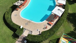 An aerial view of a swimming pool with sun loungers and umbrellas, surrounded by well-manicured lawns and hedges. - Gardahill (Soiano del Lago)